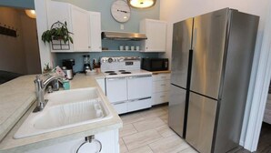 A modern kitchen with white cabinetry, a stainless steel refrigerator, a built-in oven, and a microwave.