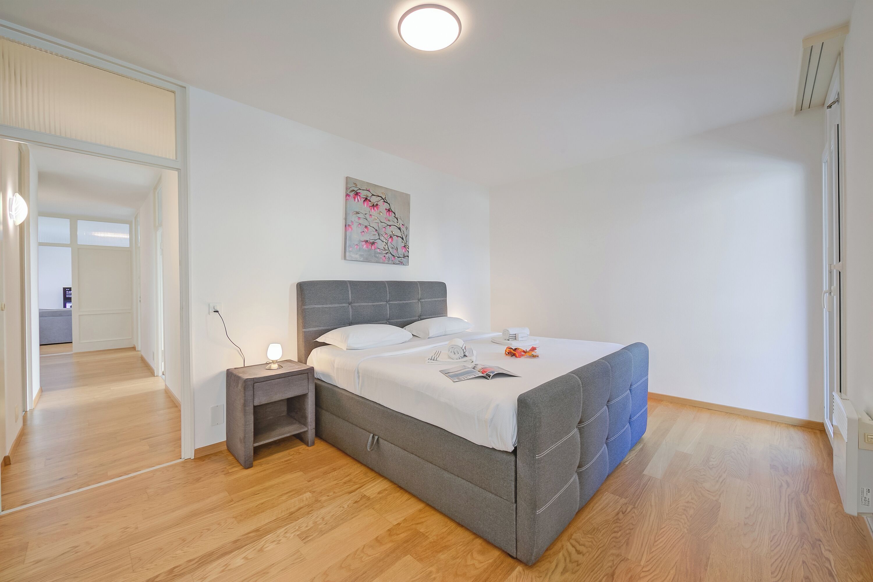 Un dormitorio con cama, mesita de noche y un cuadro en la pared.