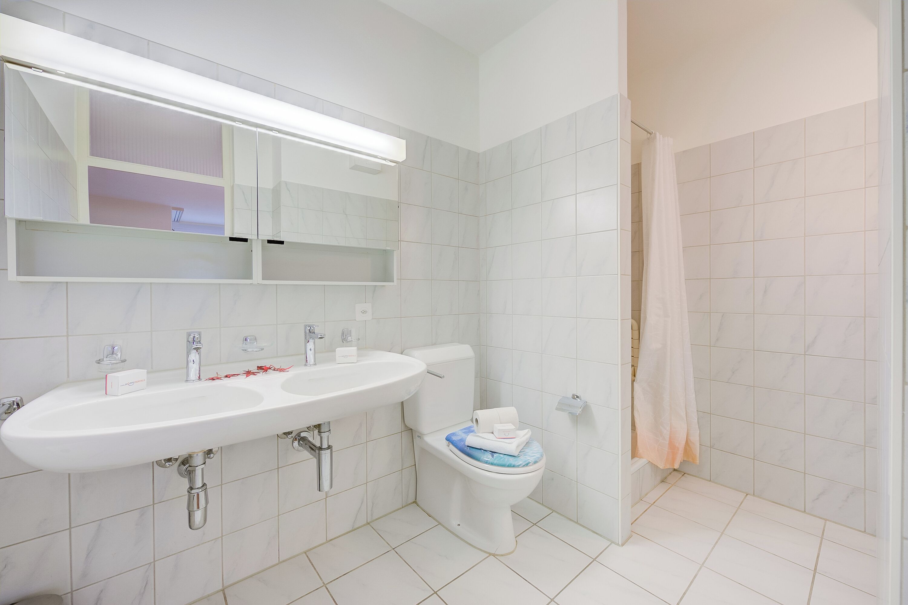 A modern bathroom with a white sink, mirror, and toilet.