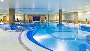 An indoor swimming pool with a curved design, multiple entry points, and a tiled floor. - Maison Privee - Premium Apartment in the Heart of JLT (Dubai)