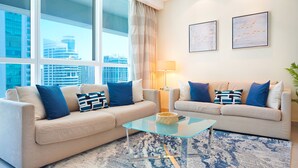 A modern living room with two beige sofas, blue and white patterned cushions, a glass coffee table, and a blue and white rug. - Maison Privee - Premium Apartment in the Heart of JLT (Dubai)