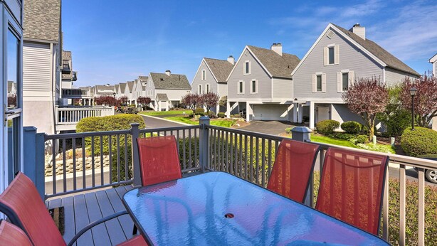 Um bairro residencial com um deck de madeira, cadeiras vermelhas e uma mesa.