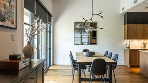Eine moderne Küche mit Holzschränken, ein Essbereich mit Holztisch und Stühlen sowie ein großes Fenster mit Meerblick.