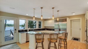 Una cocina amplia con una isla grande, taburetes de bar e iluminación colgante.