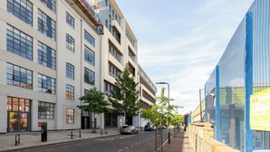 A modern building with multiple floors, large windows, and a clear sky. - Deluxe 2 Bed Flat with Balcony in Hackney (London)