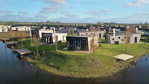 Un moderno conjunto residencial con arquitectura contemporánea, un área comunitaria central y un cuerpo de agua.