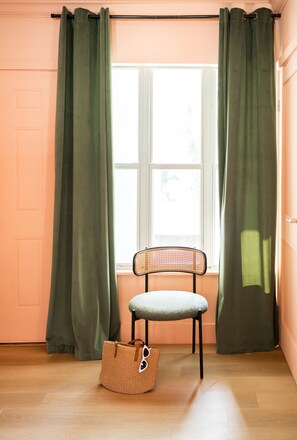 Ein Zimmer mit Fenster, Stuhl und einer gewebten Tasche.