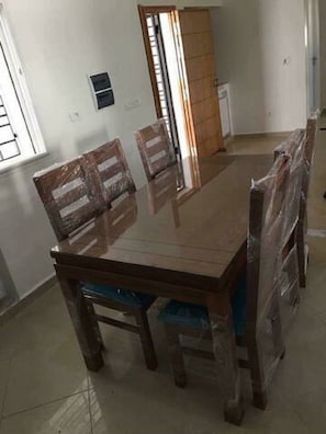 A dining room with a rectangular table and four wooden chairs.