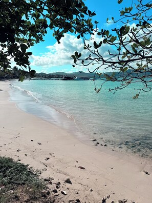 A beach with clear water, a boat dock, and a distant mountain range.