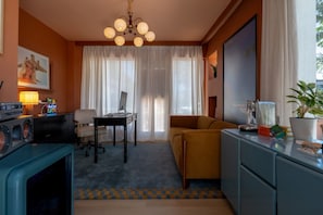 A room with a desk, chair, sofa, and a television. - Dreamy Coastal Suite with Kitchenette (Clearwater)