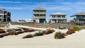 A beachfront property with multiple buildings, including a prominent tower and a house with a balcony. - New Build! Beach Front Luxury House w/Ocean Views & Breeze (Freeport)