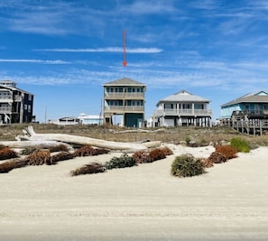 A beachfront property with multiple buildings, including a prominent tower and a house with a balcony.