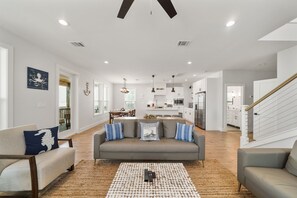 A spacious living room with a grey sofa, a coffee table, and a staircase leading to another level.