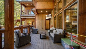 Eine Holzdielen-Terrasse mit Korbmöbeln, ein Schild mit der Aufschrift 'Broken Bow Cabin Lodging' und Blick auf den umliegenden Wald.