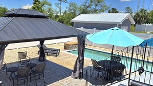 Un patio techado con mobiliario exterior, una piscina y un pabellón.