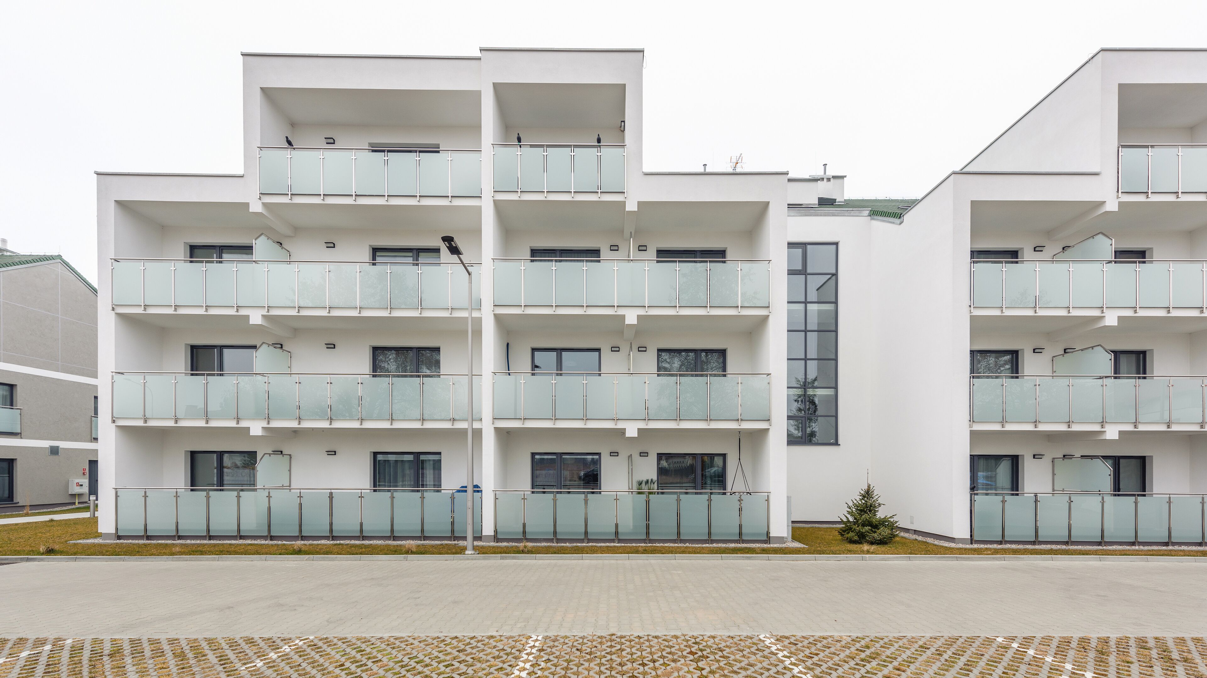 Un edificio residencial moderno de varios pisos, con balcones, ventanas amplias y techo plano.