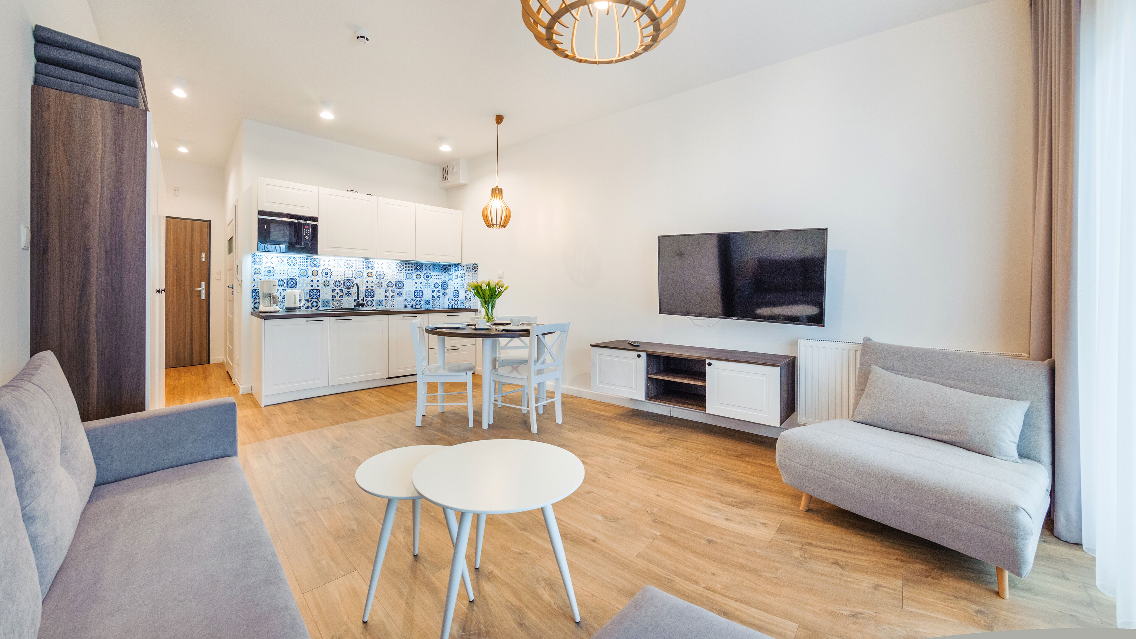A modern apartment with a living room, dining area, kitchenette, and a TV.