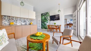 Una sala de estar moderna con comedor, cocina y ventanas amplias.