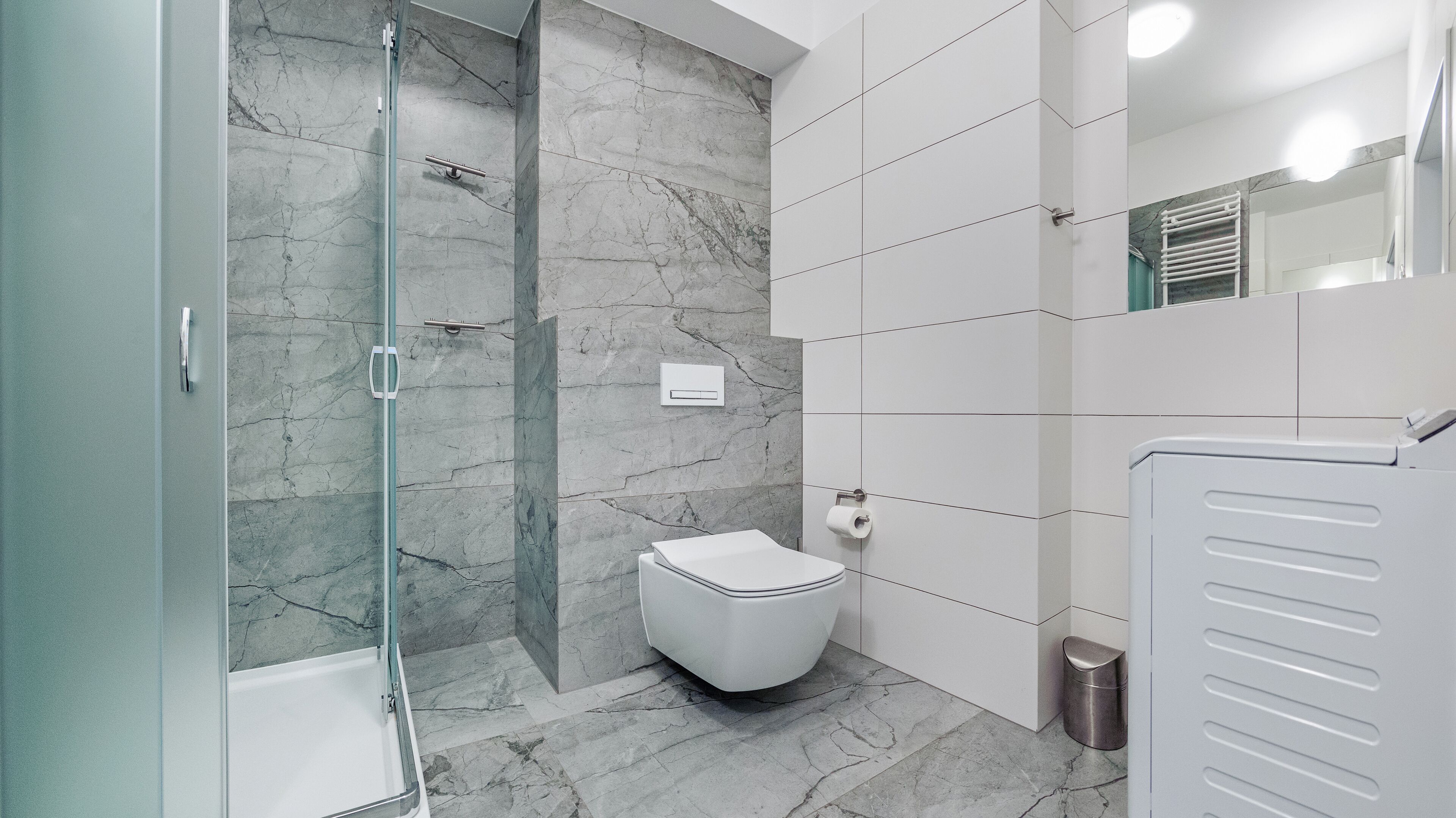 Et moderne badeværelse med en glasbrusekabine, toilet og håndvask.