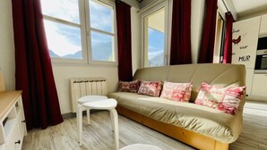 A cozy room with a sofa, a small white table, and a radiator. - Bright 50 M² With Balcony And View On The Valley (Briançon)