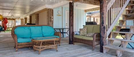 A covered porch with wicker furniture, a wooden staircase, and a clock on the wall.