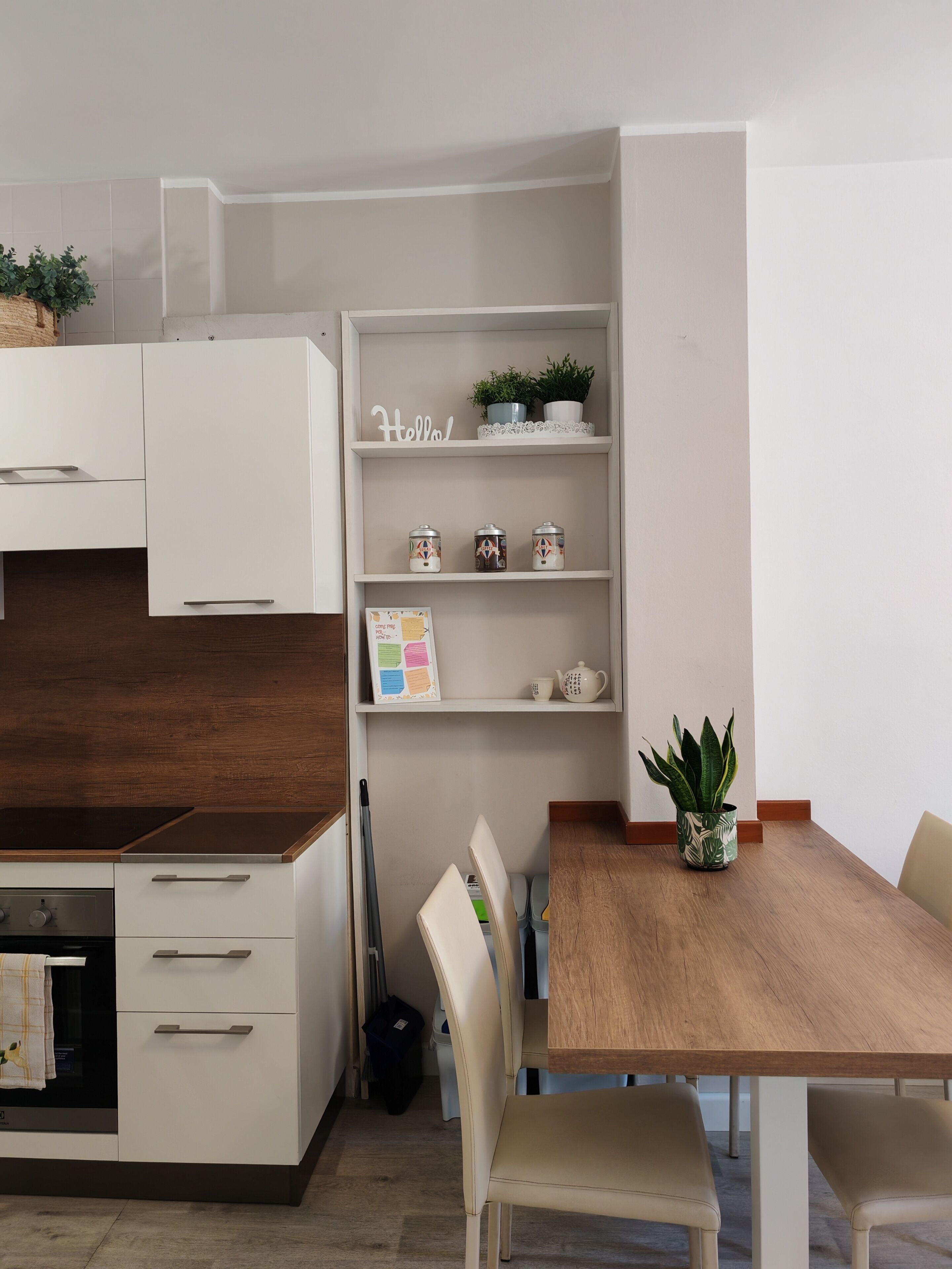 A modern kitchen with white cabinetry, a wooden countertop, and a dining area with a wooden table and chairs.