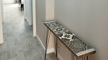 A hallway with a patterned bench, a door leading to another room, and decorative wall art.