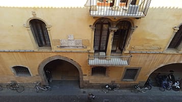 A building with a balcony, arched windows, and a stone facade.