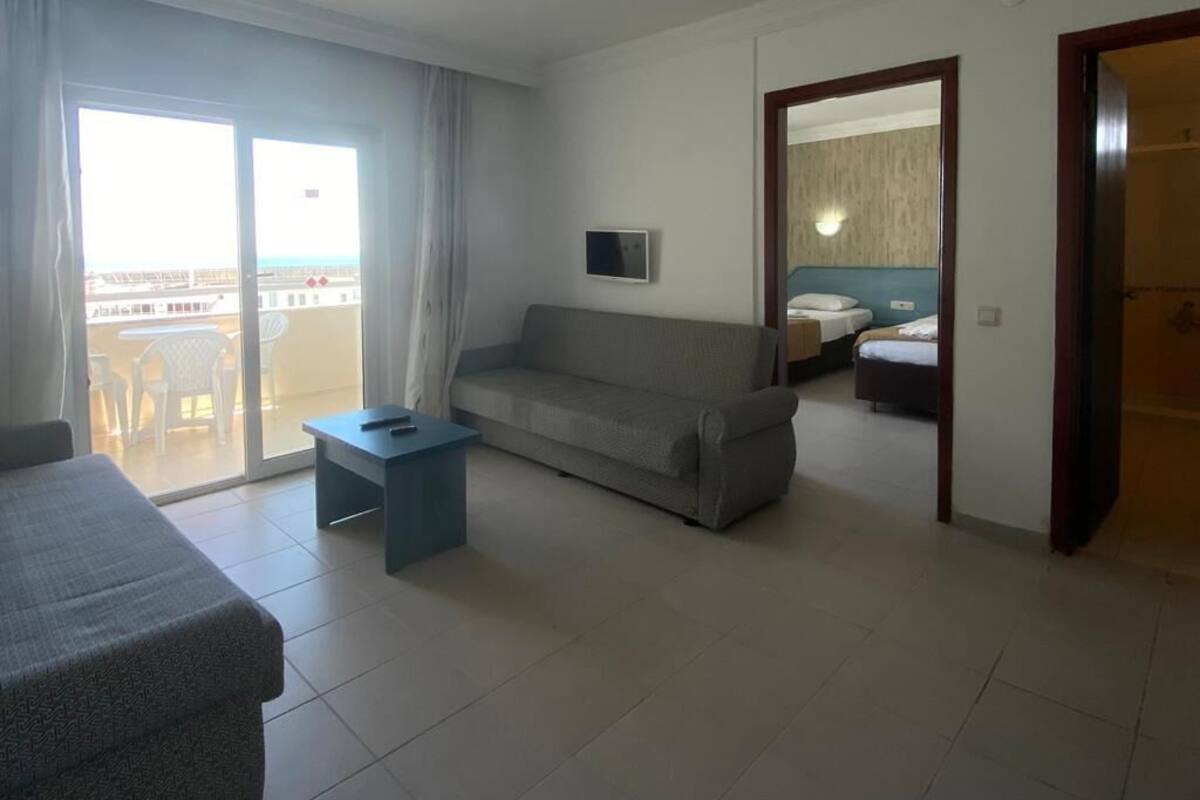 Une chambre d’hôtel équipée d’un canapé, d’une petite table, d’un lit avec une tête de lit et d’une porte-fenêtre coulissante donnant sur un espace extérieur.