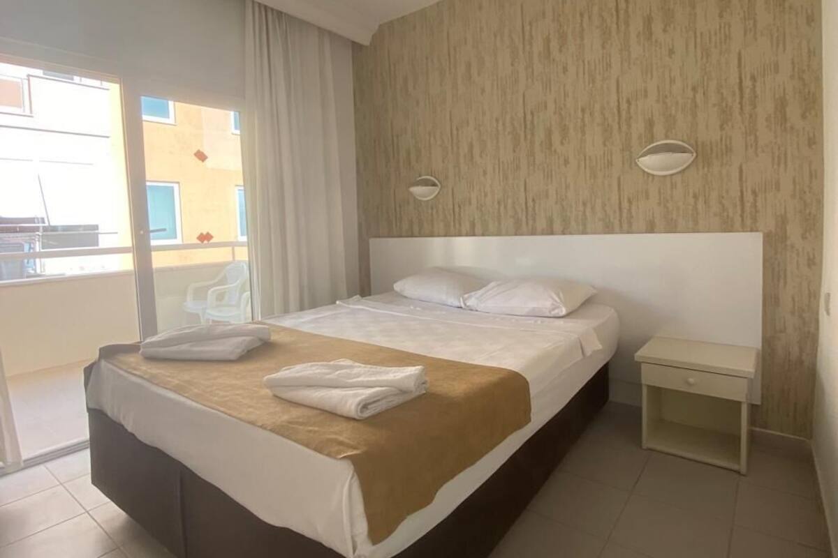 Une chambre d’hôtel avec un grand lit, une table de chevet et une vue sur le balcon extérieur.