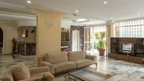 Amplia sala de estar con un sofá color beige, una mesa de centro y un televisor de pantalla plana montado en un mueble de madera.