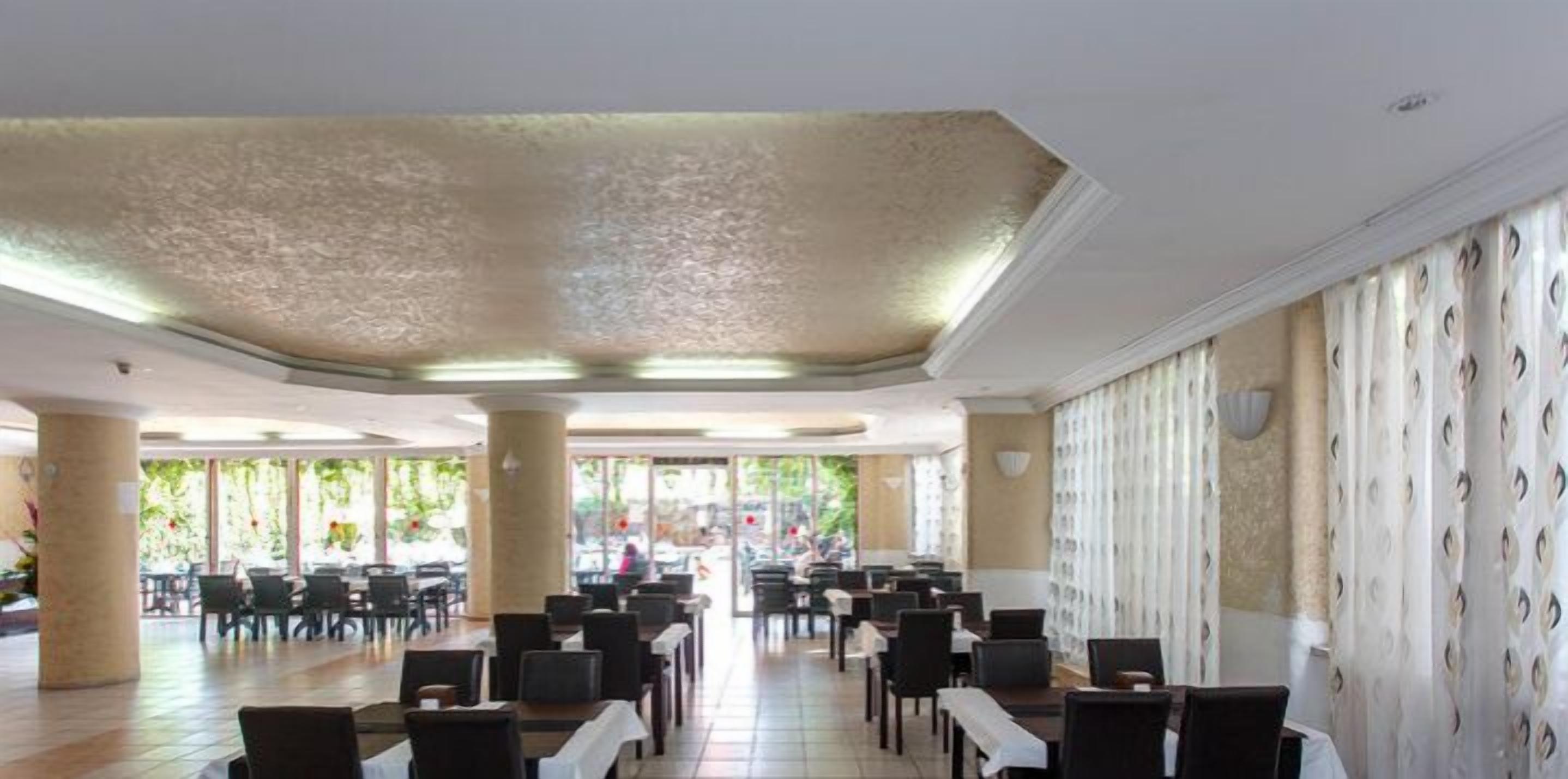 A spacious indoor area with multiple tables and chairs, large windows, and a patterned wall.