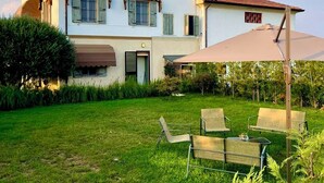 Een twee verdiepingen tellend huis met een grote tuin, een pergola en buitenmeubels.