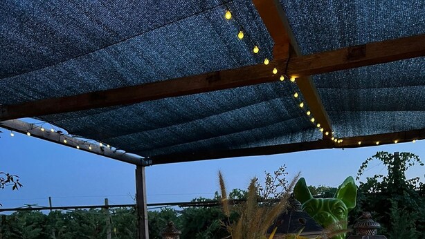 Een terras buiten met lichtslingers, kaarsen en lantaarns.