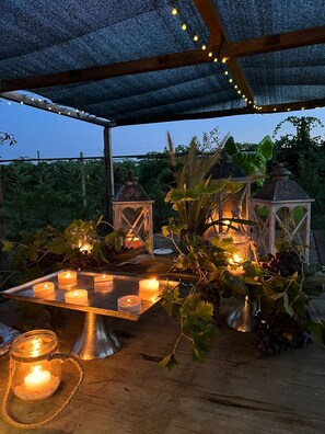 Une terrasse extérieure décorée de guirlandes lumineuses, de bougies et de lanternes.