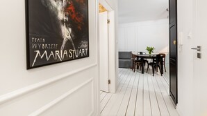 A hallway with a framed poster, a dining area with a table and chairs, and a white door. - Happy Stay Old Town Tartaczna St. 314 (Gdansk)