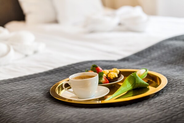 A tray with a cup of coffee, strawberries, and pastries on a bed.