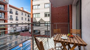 A balcony with a wooden table and chairs, a small pool, and a view of neighboring buildings. - Happy Stay Old Town Tartaczna St. 314 (Gdansk)