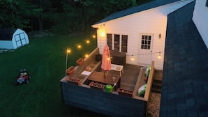Ett litet hus med en veranda, utomhusmöbler och ljusslingor.