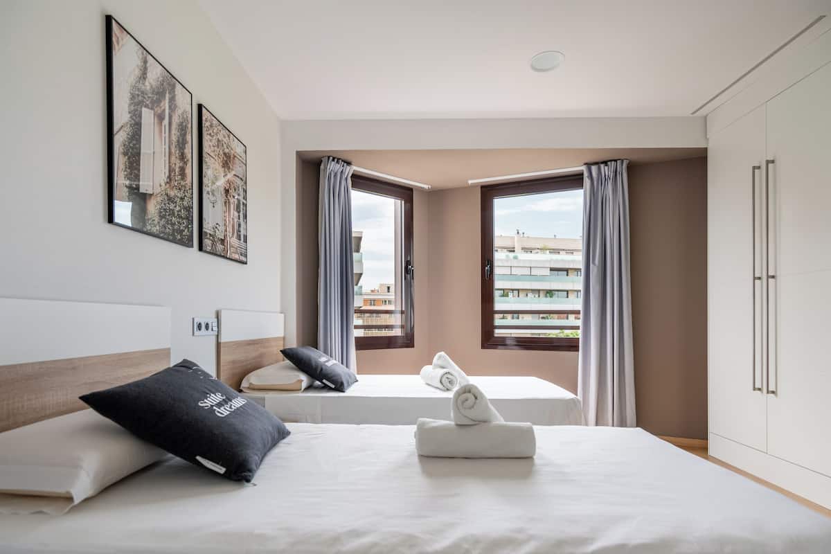 Habitación de hotel con dos camas, vistas a edificios y un armario.