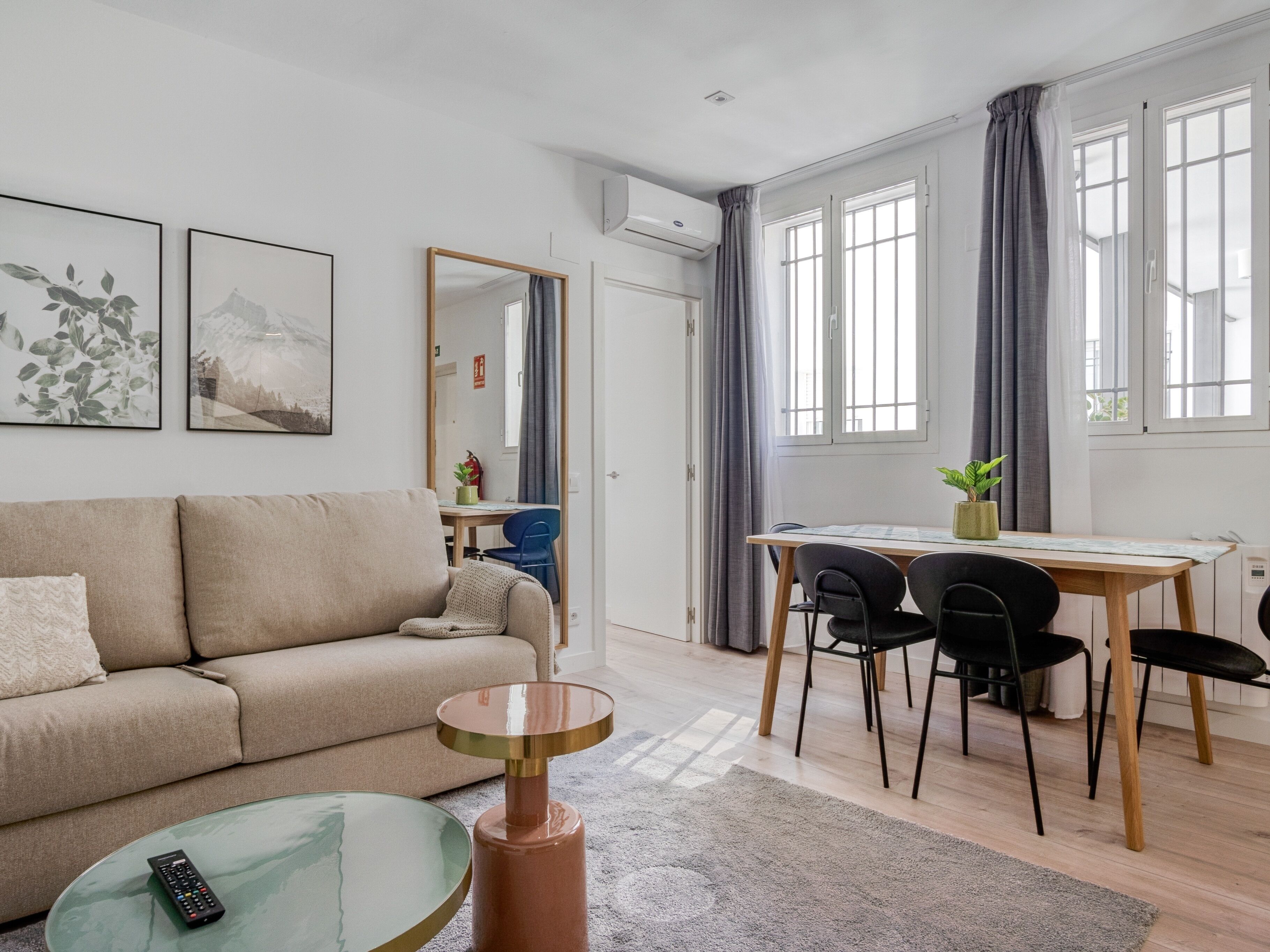 A modern living room with a sofa, a coffee table, and a dining area with a table and chairs.