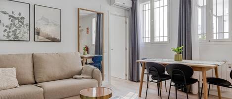 A modern living room with a sofa, a coffee table, and a dining area with a table and chairs.