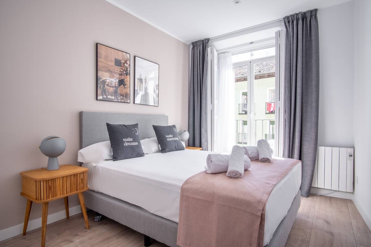 A modern bedroom with a bed, bedside tables, and artwork on the wall.