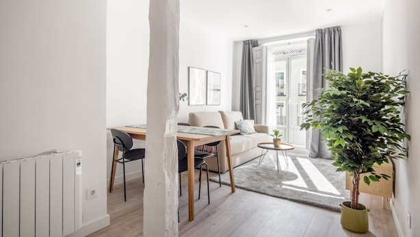A modern living room with a dining area, a sofa, a coffee table, and a potted plant. - Limehome Madrid Calle Ave María (Madrid)