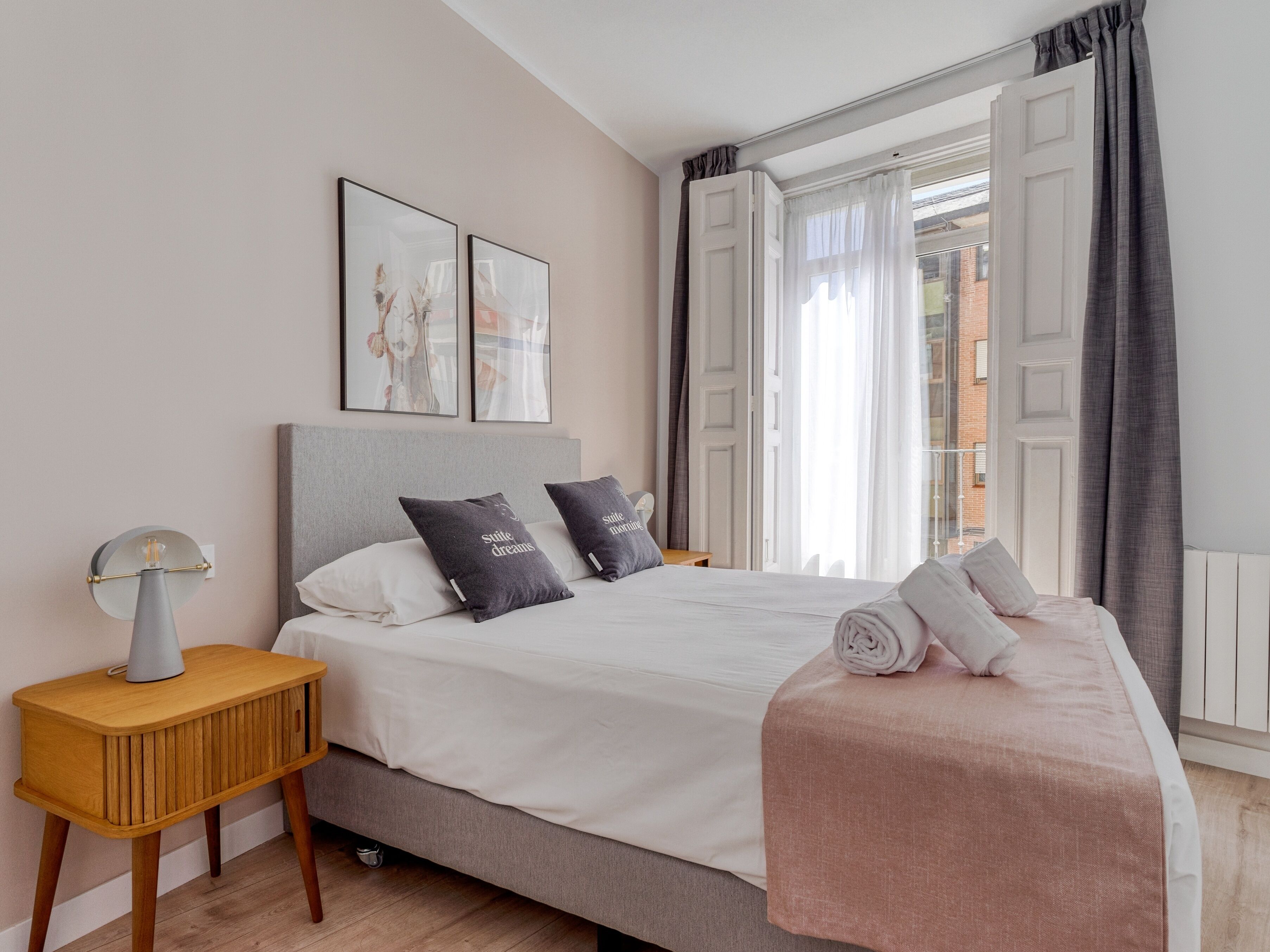 Een keurig opgemaakt slaapkamer met een bed, nachtkastje en uitzicht.