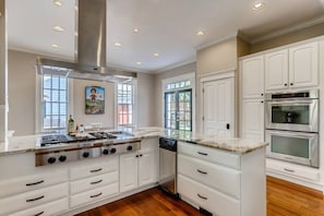 A kitchen with white cabinets, a stainless steel range hood, and built-in appliances.