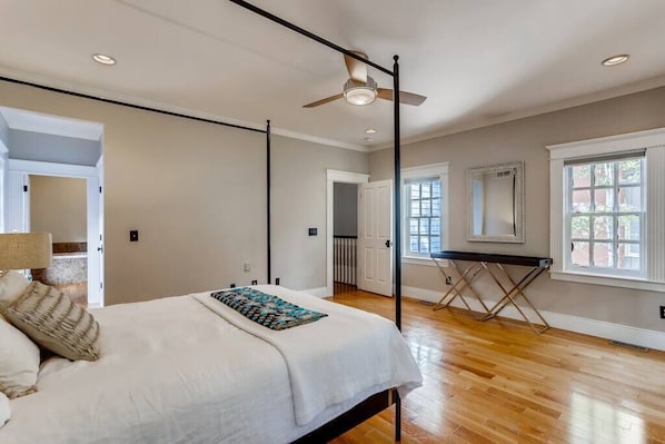 A bedroom with a bed, a ceiling fan, a window, and a door.