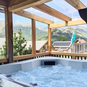 A hot tub with a mountain view, wooden beams, and a solar panel on a roof. - Premium Chalet # 14 with IR-Sauna & Whirlpool (Hohentauern)