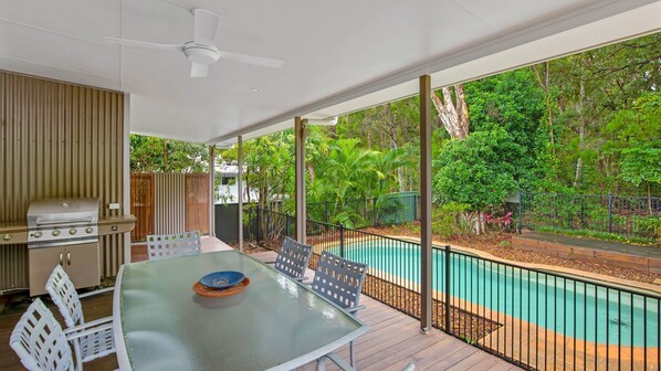Relax by the pool in this outdoor space, featuring a table, chairs, and barbecue grill.