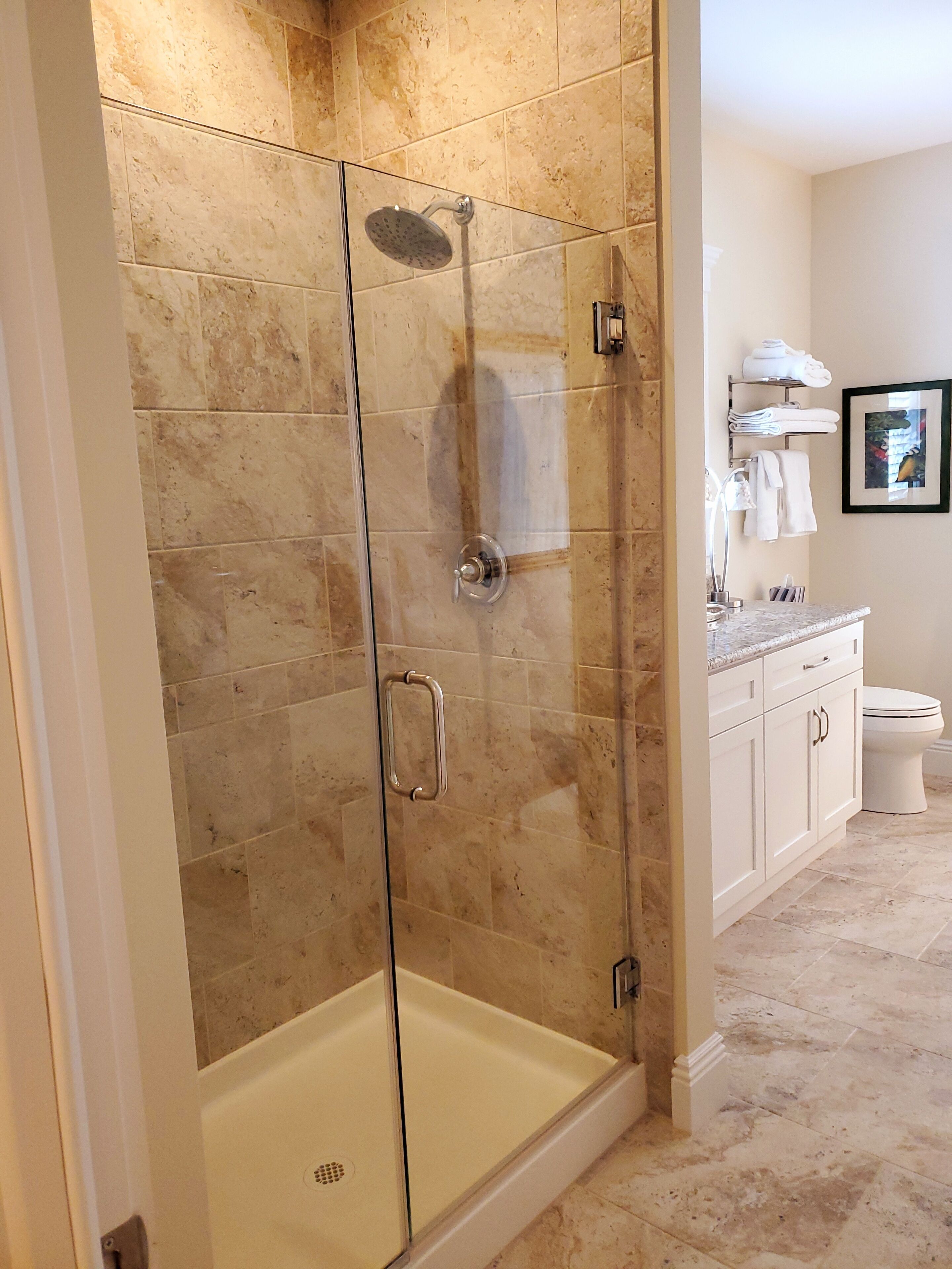 A modern bathroom with a glass-enclosed shower, white cabinetry, and a toilet.
